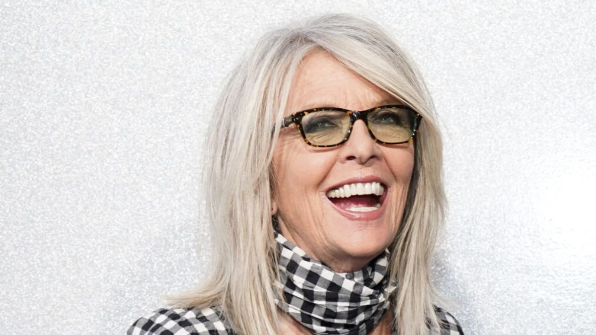 Diane Keaton în prim-plan, zâmbind, recunoscută pentru stilul său iconic cu pălărie și costum