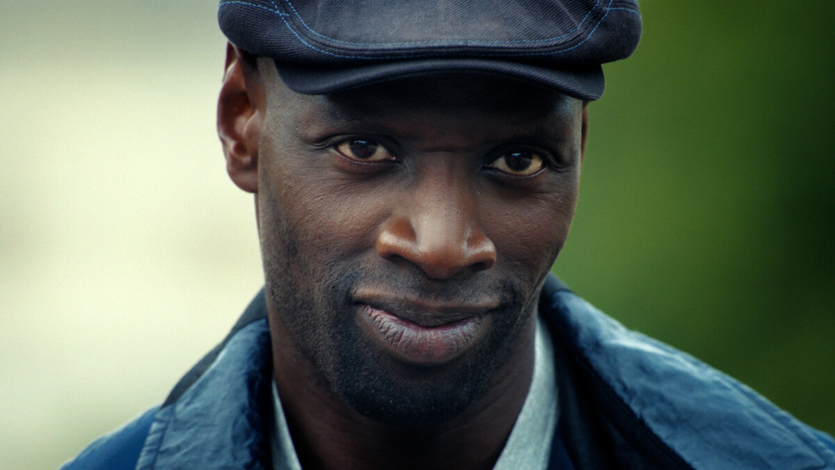 Omar Sy în rolul lui Assane Diop, cu șapcă și jachetă albastră, în Lupin, partea 4