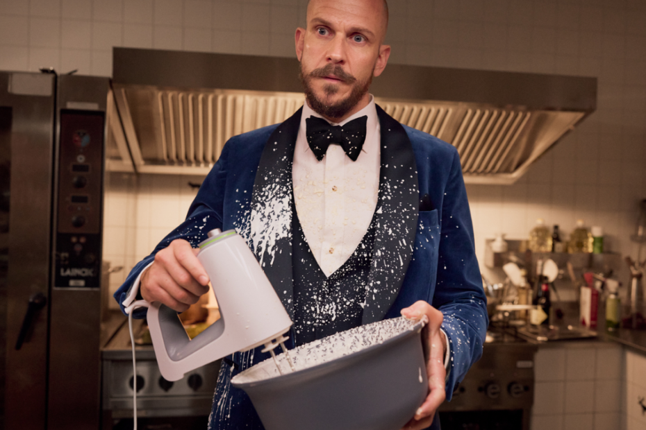 Gustaf Skarsgård în rolul lui Filip, ținând un bol și un mixer în comedia Furtuna.